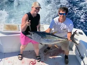 Young lady holding up huge yellowfin tuna she caught during her Corolla vacation trip.
