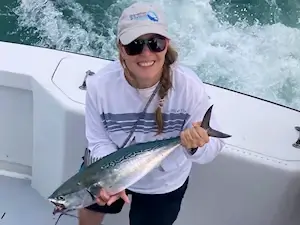 Pretty lady vacationing angler holds a nice albacore.
