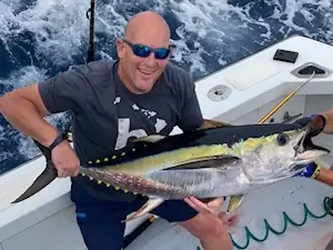 Happy angler vacationing in KDH holds up a colorful yellowfin tuna for pictures.