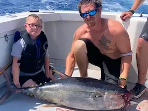 Young angler on a Kitty Hawk vacation sits by a nice yellowfin tuna.