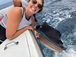 Pretty young lady angler helping release a sailfish she just caught.