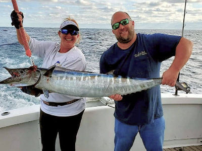 Nage Head vacationer holds up nice wahoo he just caught.